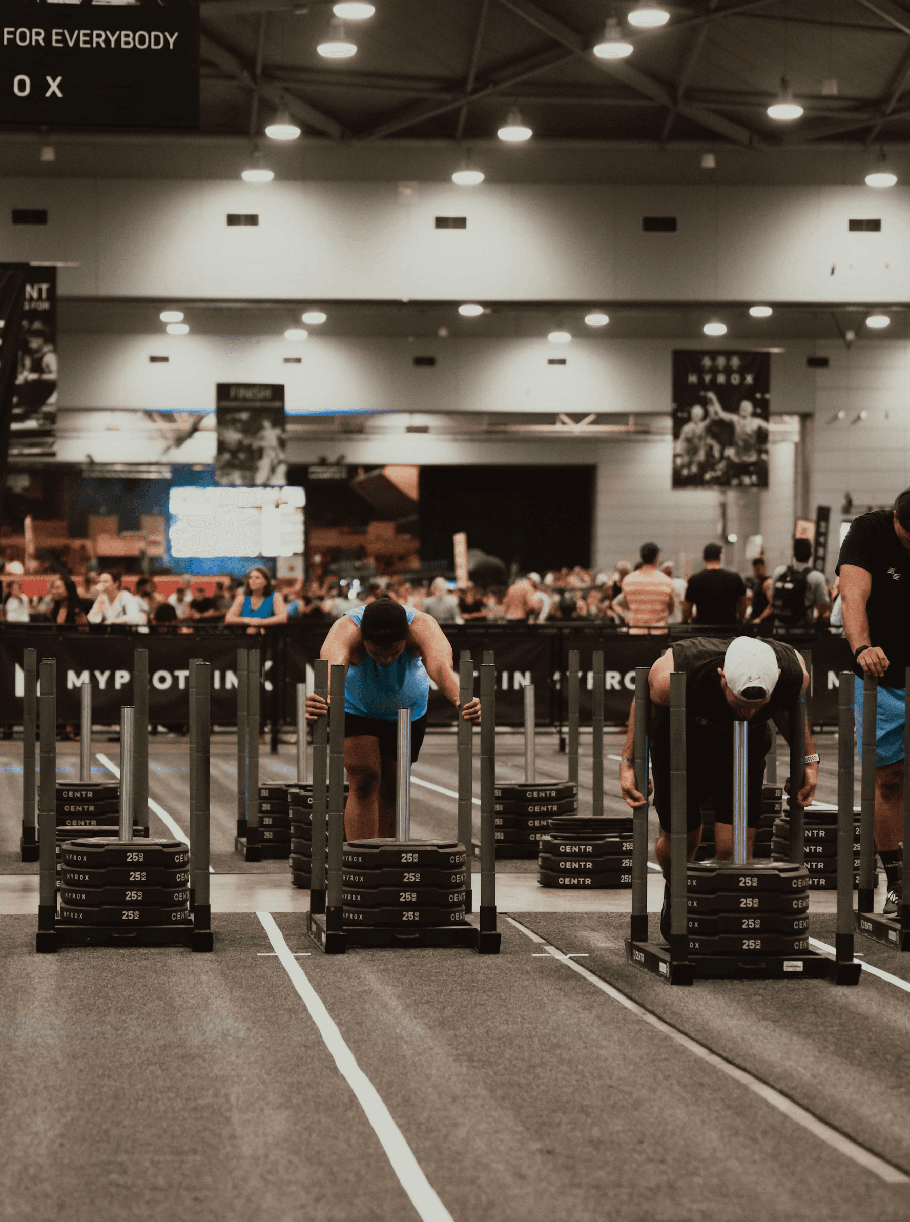 An APX Velocity coach driving an athlete through a sled push, one of the HYROX stations, in Menlo Park