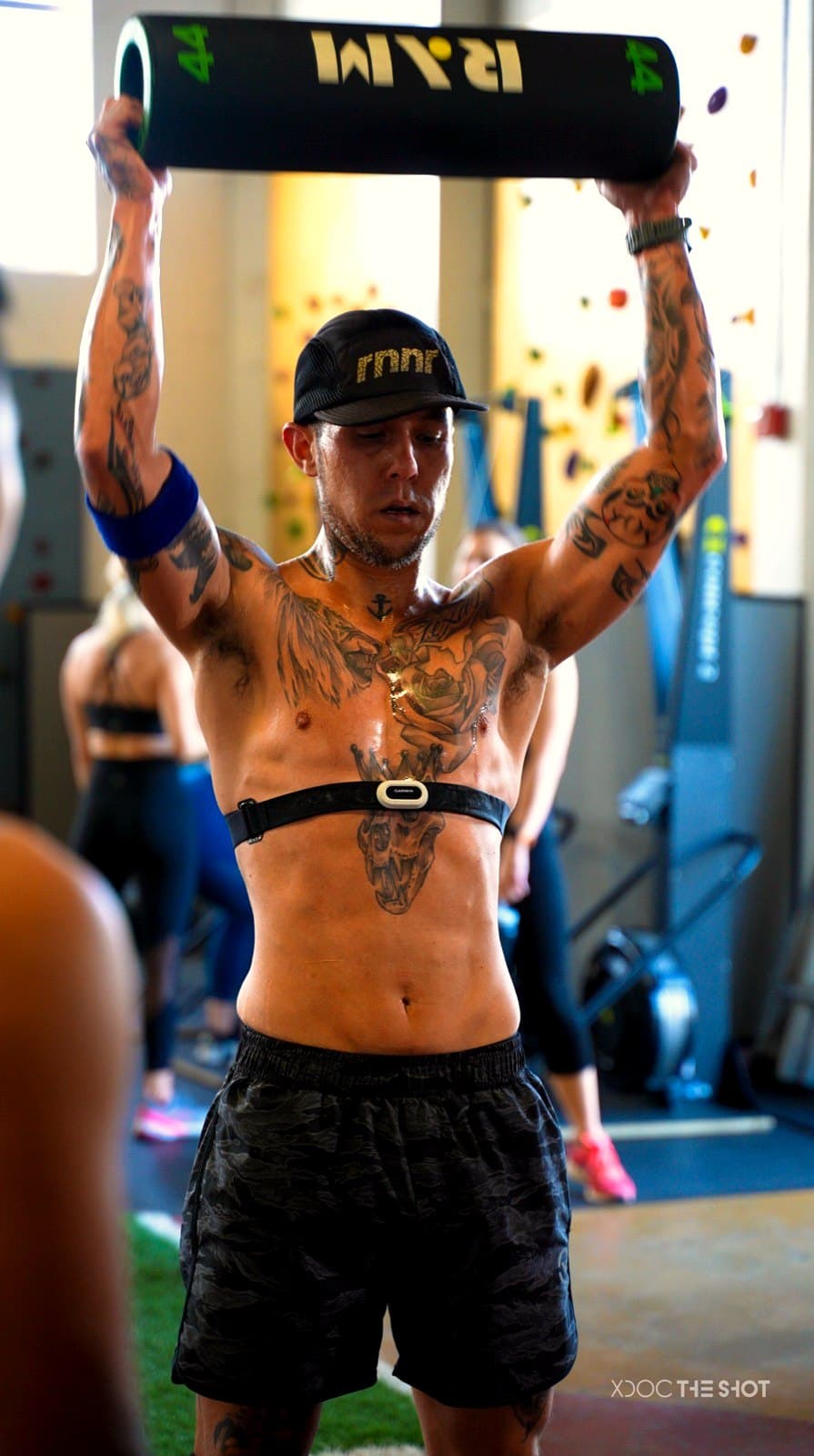 An APX Velocity athlete pressing a weighted log overhead at a DEKA event