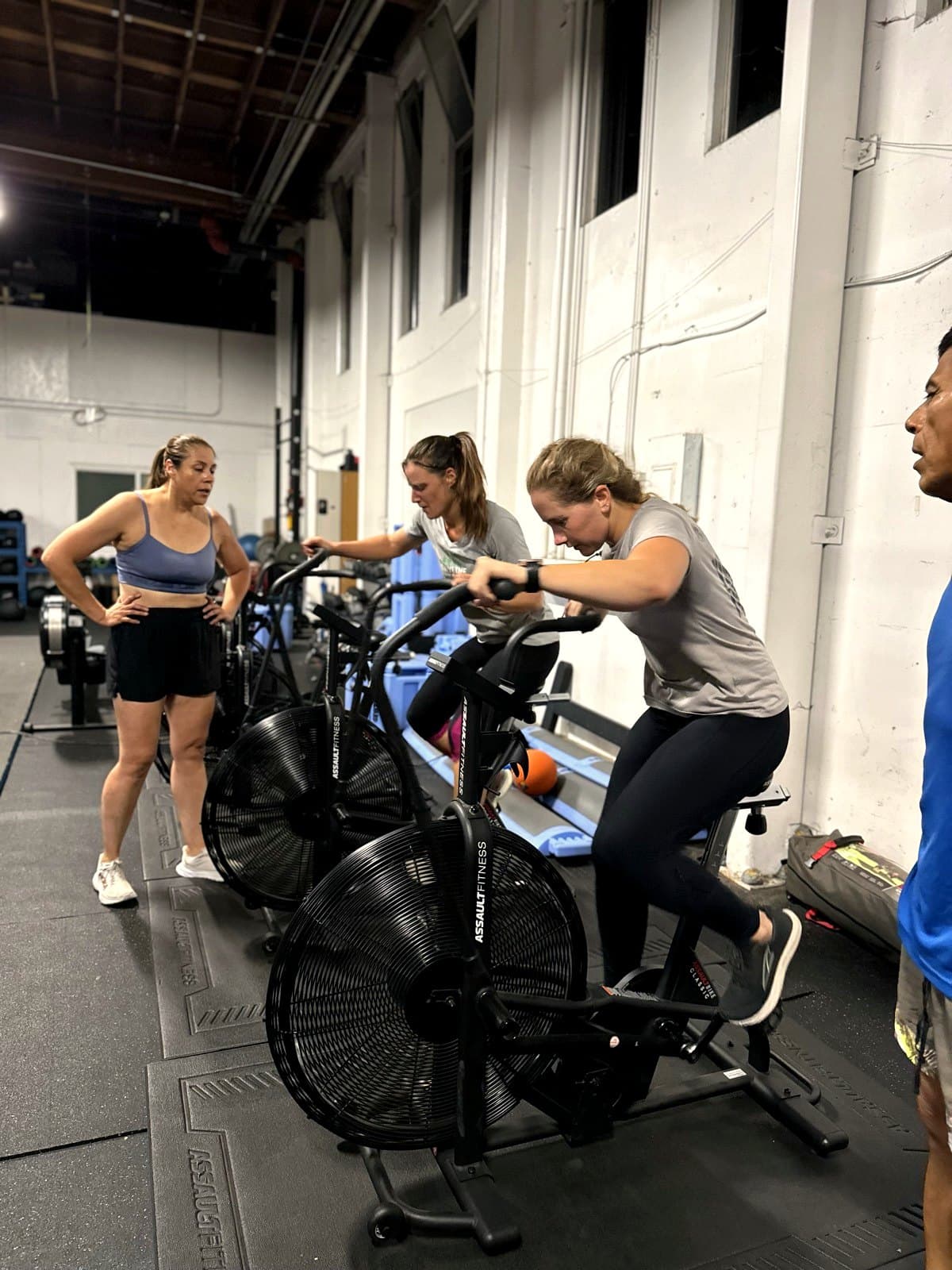 Members powering through assault bike intervals during a group class